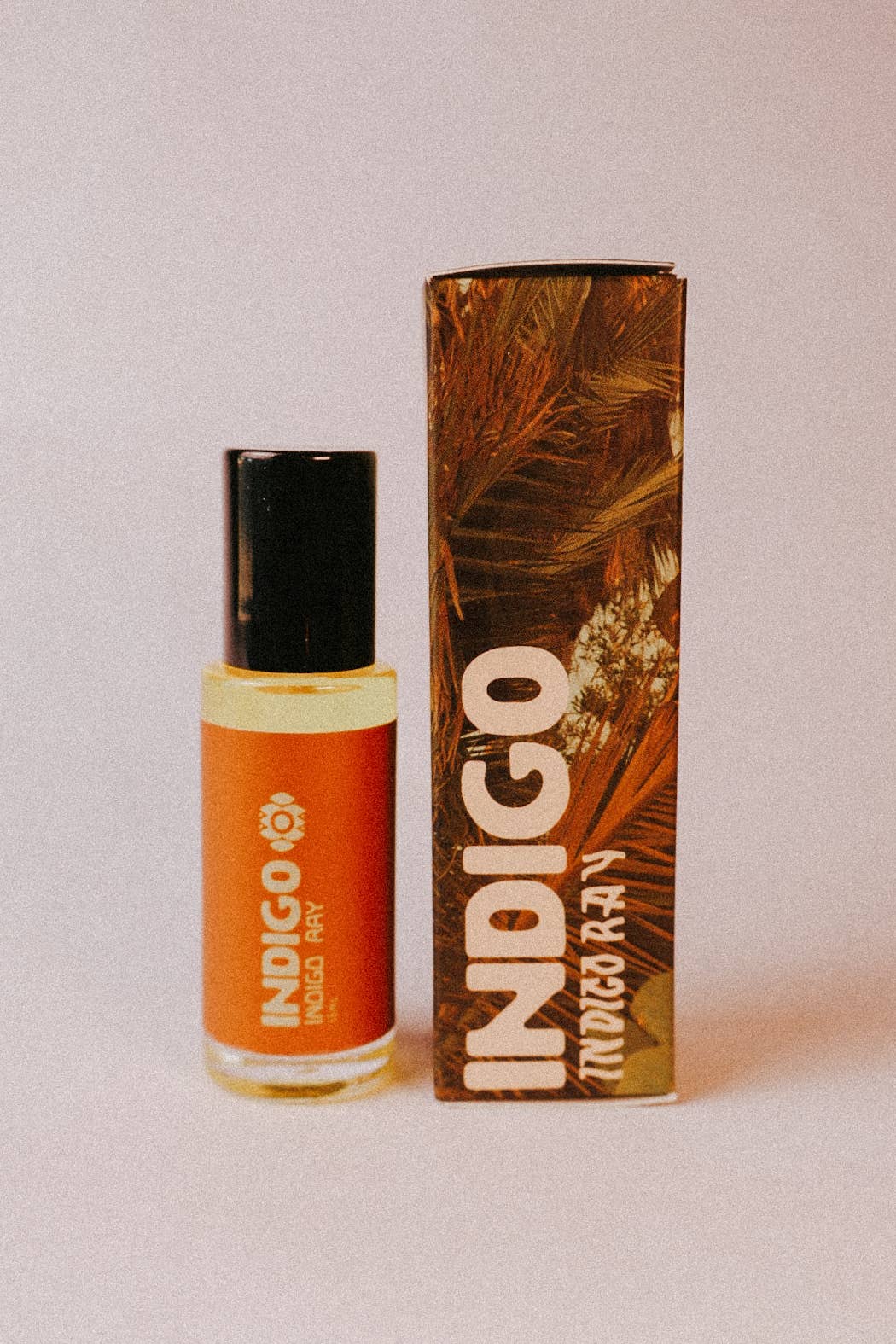 Indigo botanical perfume roller featuring warm citrus amber tones and luxe palm inspired packaging