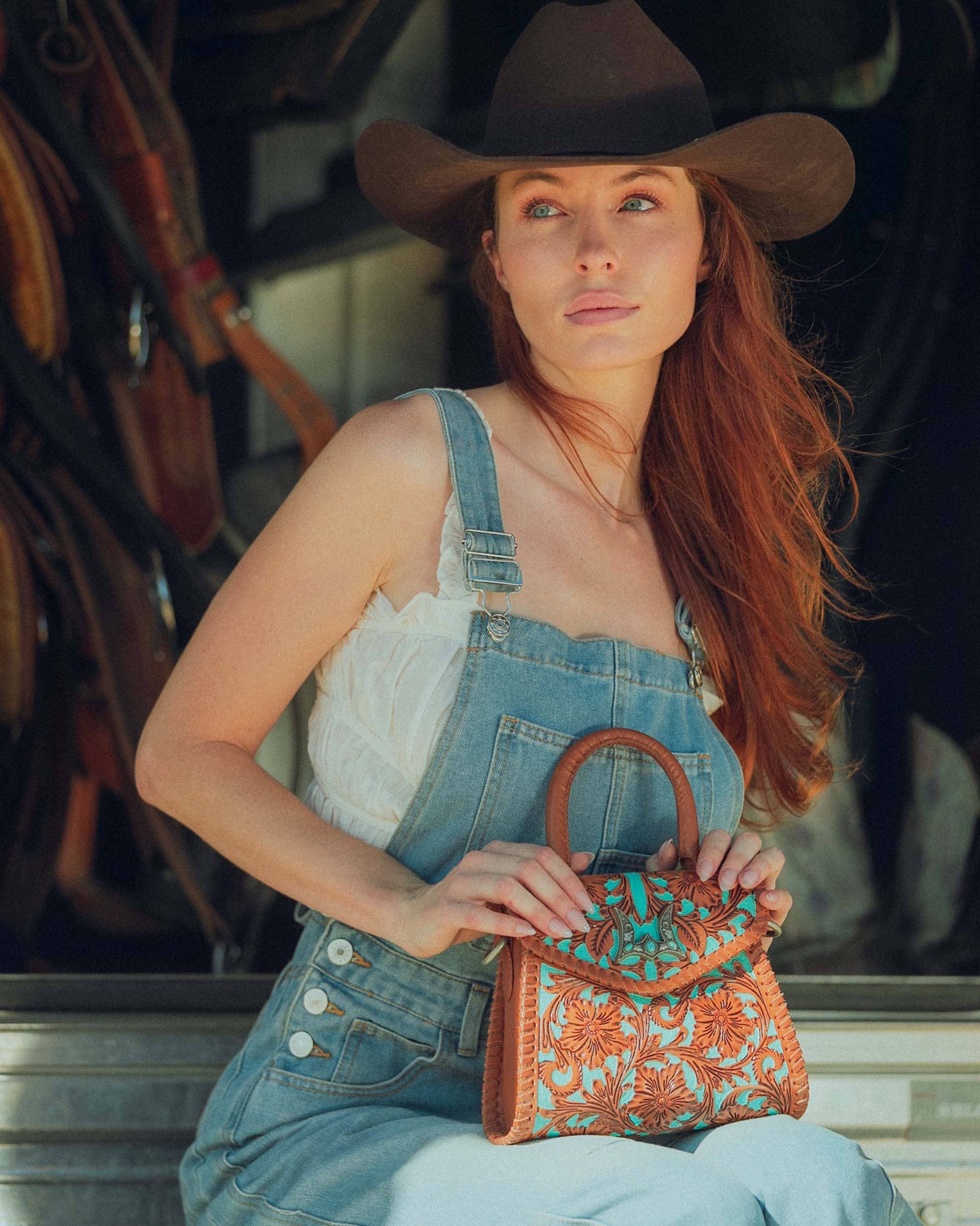 Western tooled mini handbag with turquoise floral detailing and wooden top handle styled in a rustic western setting