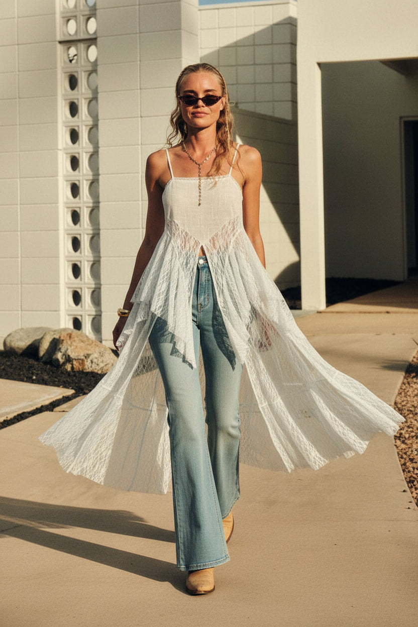 woman wearing sheer white lace flyaway maxi cami top with front slit layered over flared denim jeans styled in boho western outfit