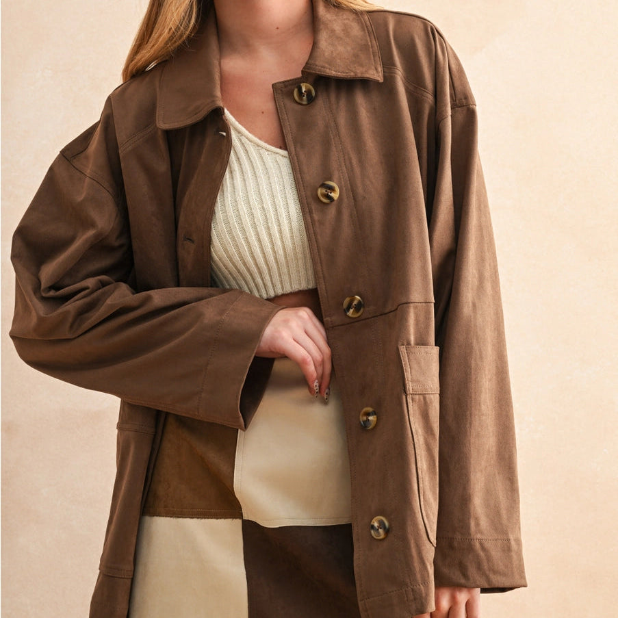 Woman wearing a brown coat over a white top and beige skirt on a beige background