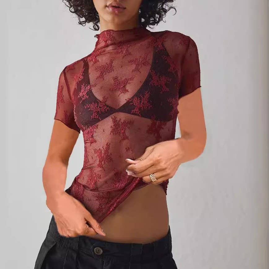 Person wearing a sheer burgundy lace top against a plain background