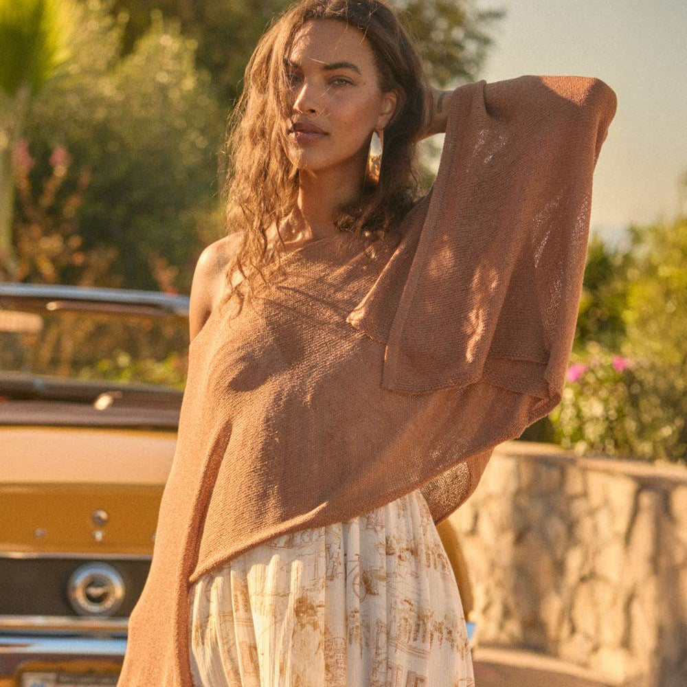woman wearing lightweight brown knit poncho sweater over flowy boho skirt styled outdoors with vintage car western boho look