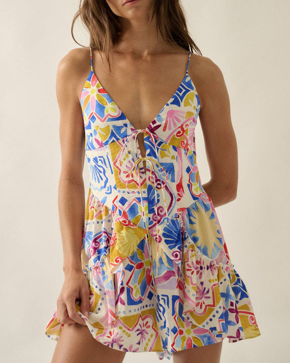 Woman wearing a colorful floral dress against a plain background